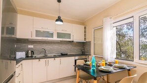 Una cucina moderna con mobili bianchi, un piano di lavoro nero e una finestra vista alberi.