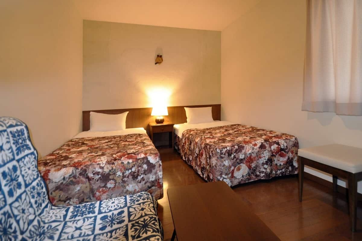 Habitación de hotel con dos camas, una mesita, una silla y un calentador.