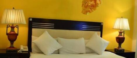 A bed with white linens, two bedside lamps, and a hanging light fixture.