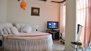 A hotel room with a bed, a television, a desk with a computer, and a window with curtains. - Lewi Hotel Piazza (Awassa)