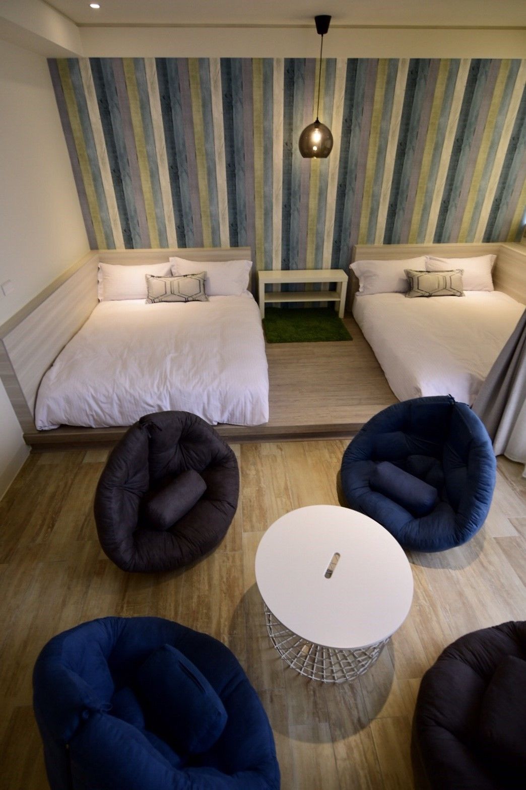 A room with two beds, a small table, and four bean bags.