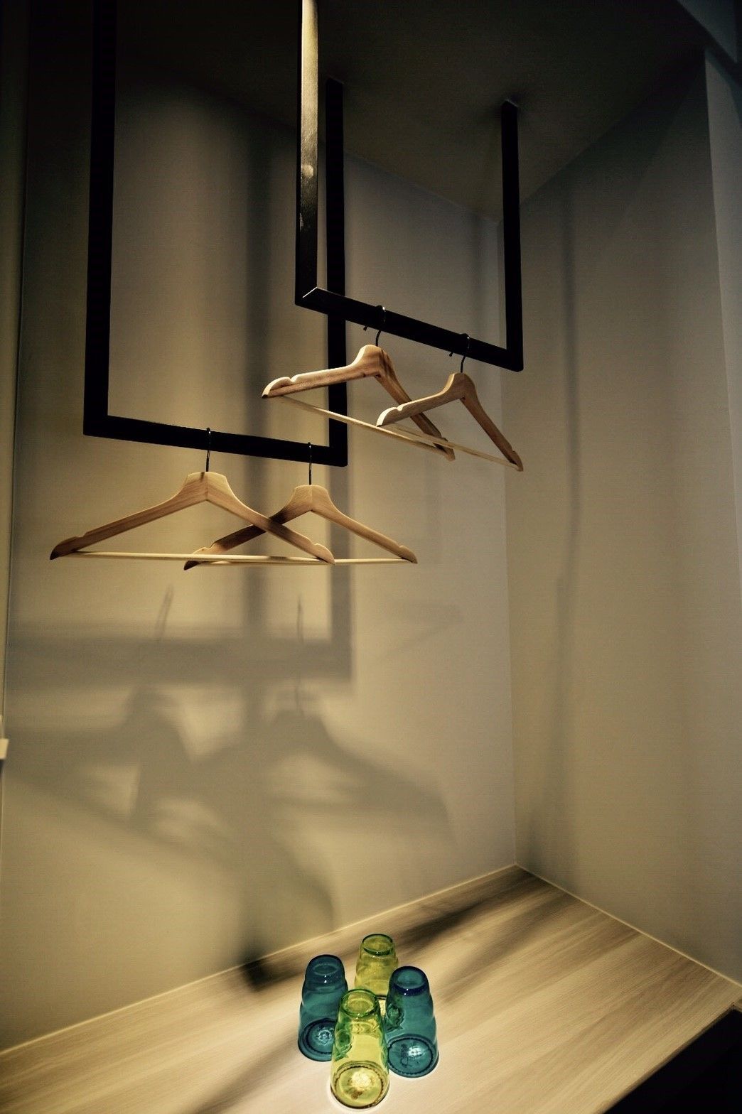A closet with wooden hangers and a shelf with clear glass bottles.