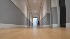 Un long couloir étroit, doté d’un plancher en bois et de murs blancs.