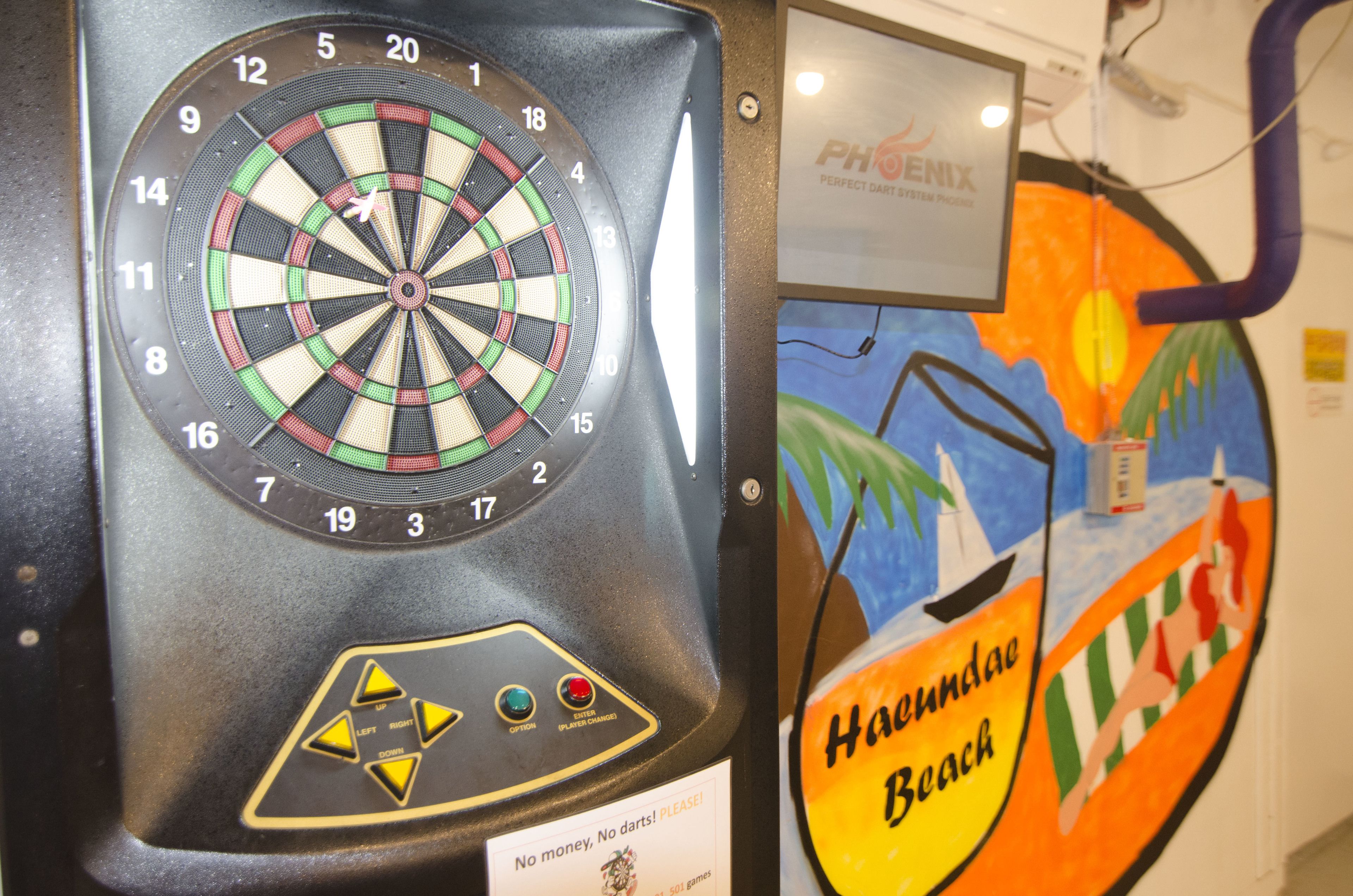 A dartboard with a dartboard and a sign that says "No money, no darts! PLEASE!"