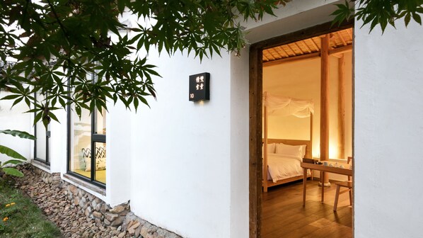 A traditional Japanese-style room with a wooden bed, a small table, and a window with a view of a garden. - Floral Hotel Songyang Niaoshe (Lishui)