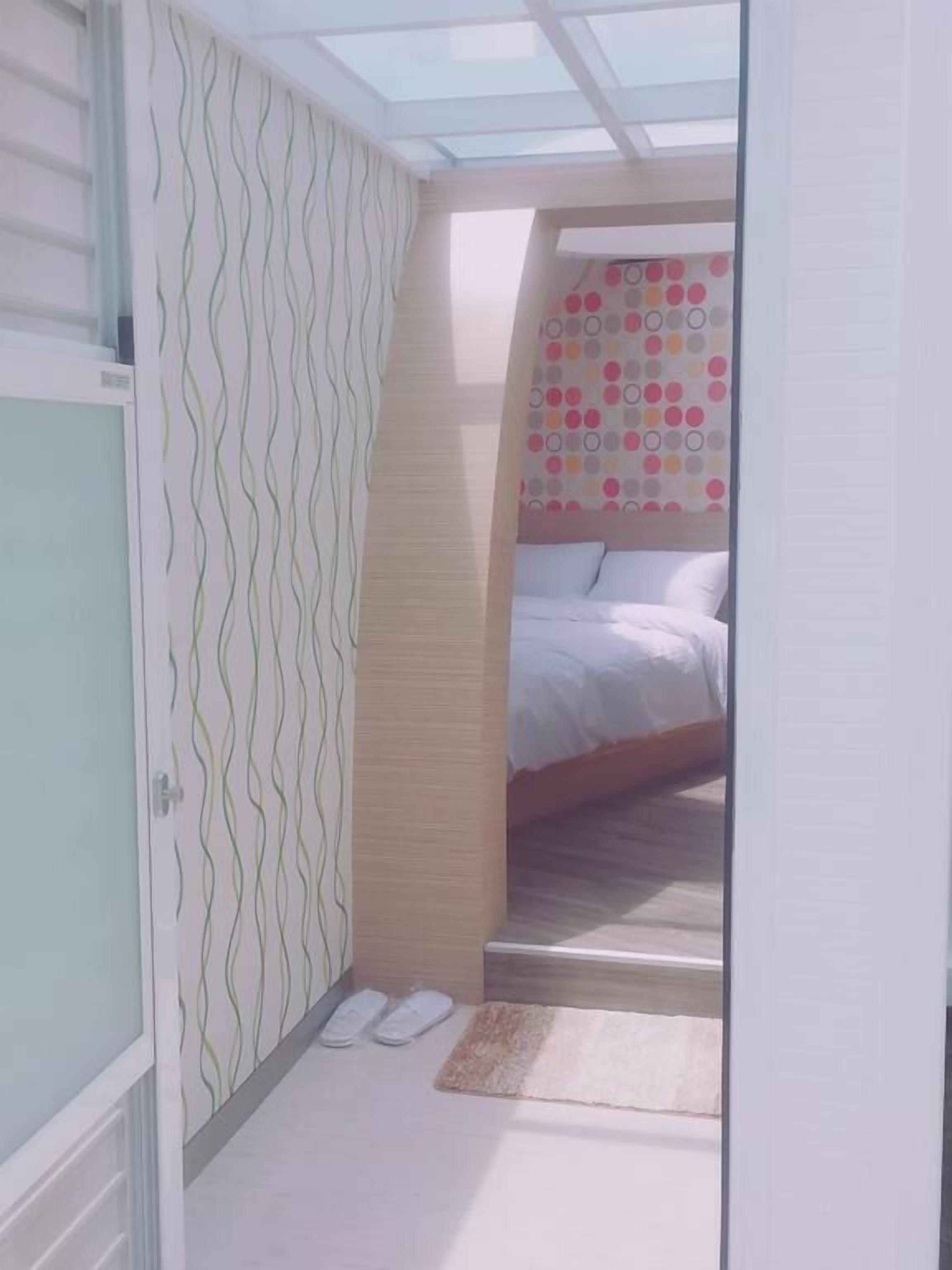 A bedroom with a bed, a patterned wall, a window, and a door.