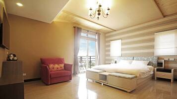 A modern bedroom with a large bed, a red armchair, and a balcony with a view.
