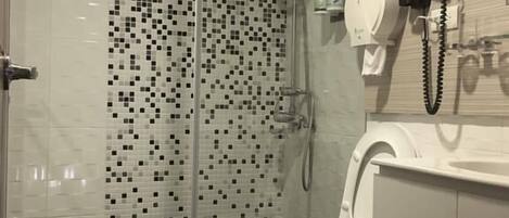 Un baño moderno con ducha de vidrio, inodoro blanco y lavamanos con forma de teléfono.