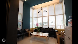 Una sala de estar moderna con un sofá, sillas, una mesita de centro y un refrigerador.