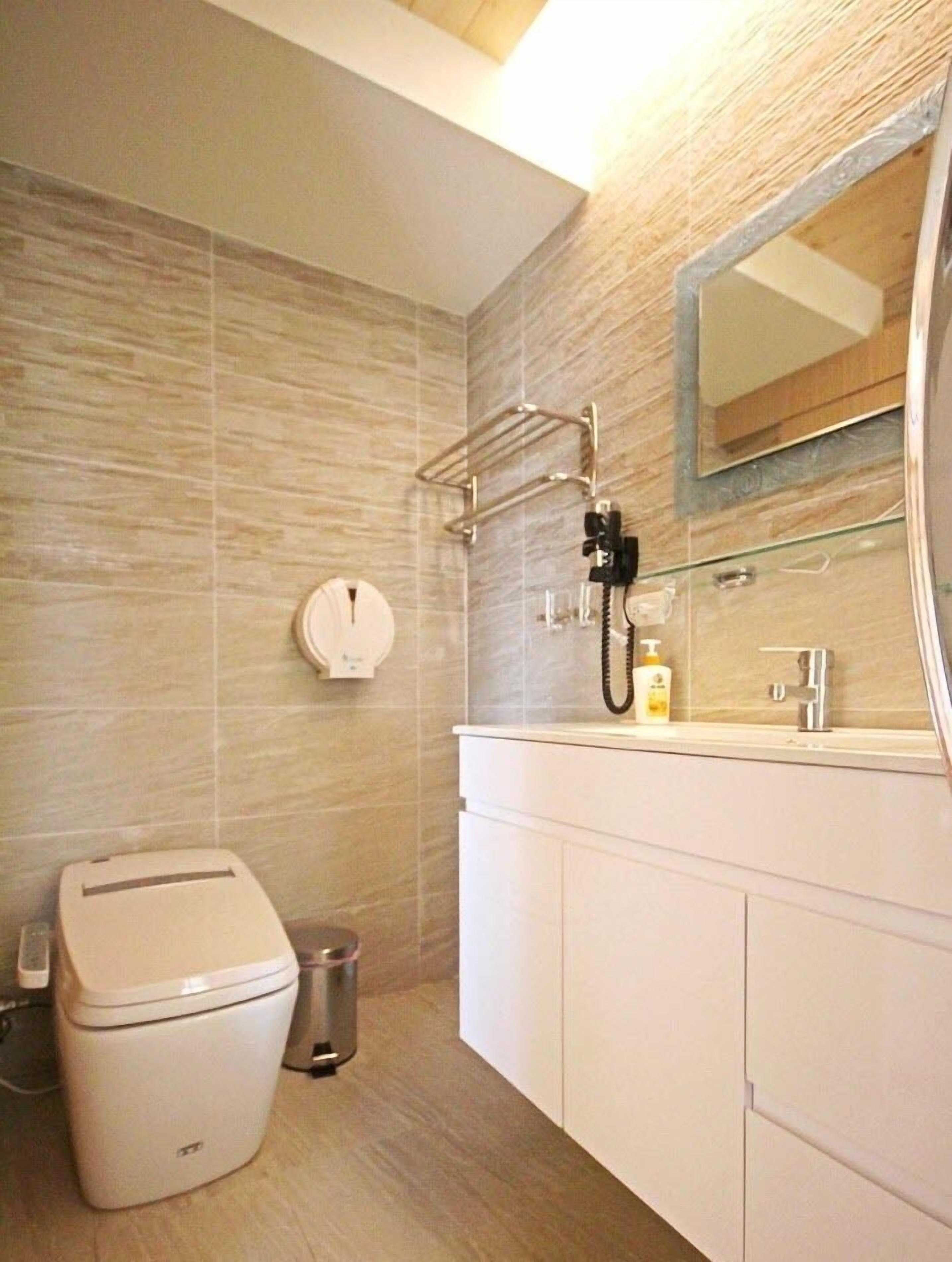 A modern bathroom with a toilet, sink, and mirror.