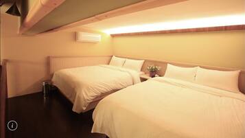 A hotel room with two beds, a bedside table with a vase of flowers, and a wall-mounted air conditioner.