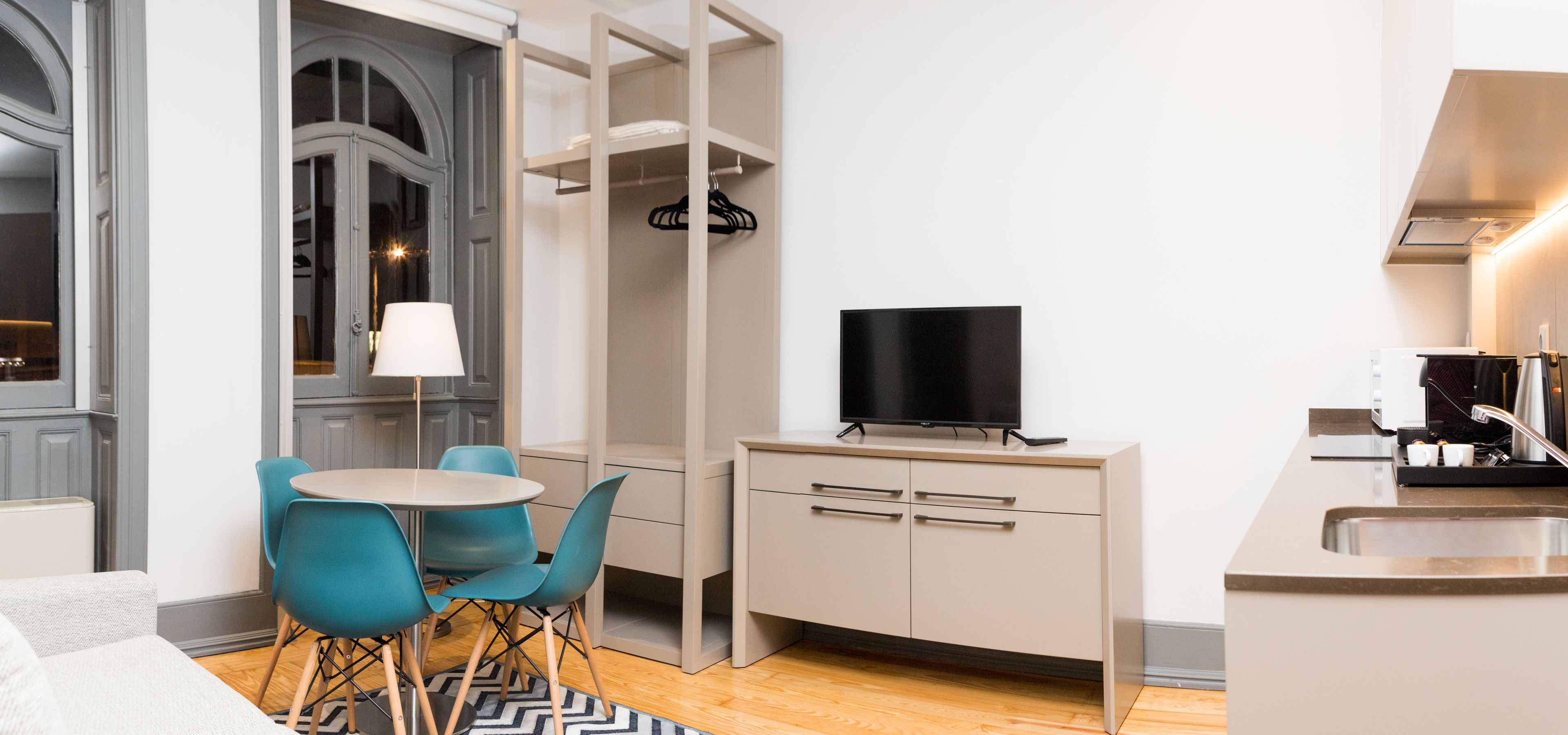 A compact kitchen with a dining area, a TV, and a modern sink.