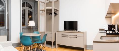 A compact kitchen with a dining area, a TV, and a modern sink.