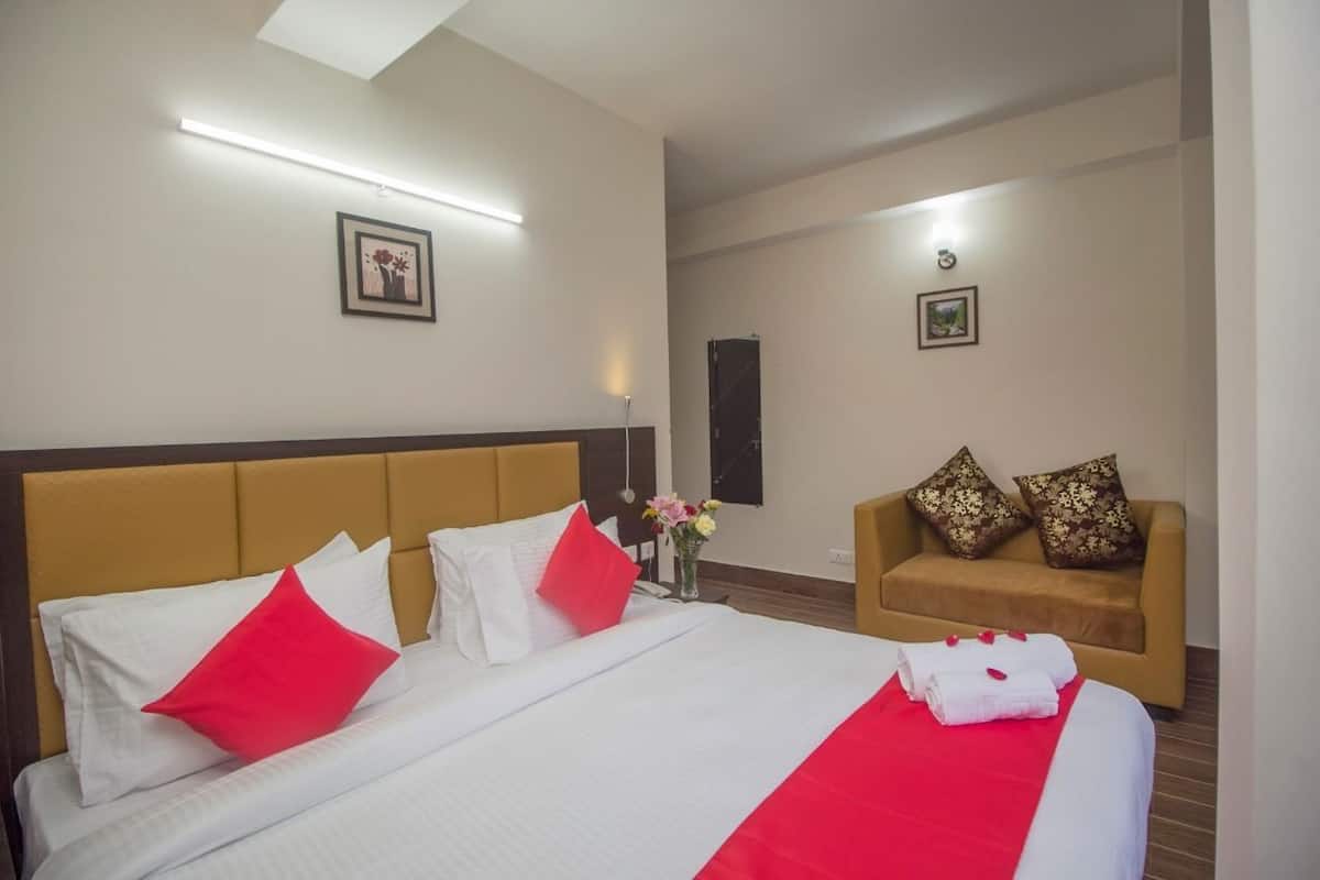 Ein Hotelzimmer mit einem großen Bett, einer Couch und einem kleinen Tisch mit Blumen.