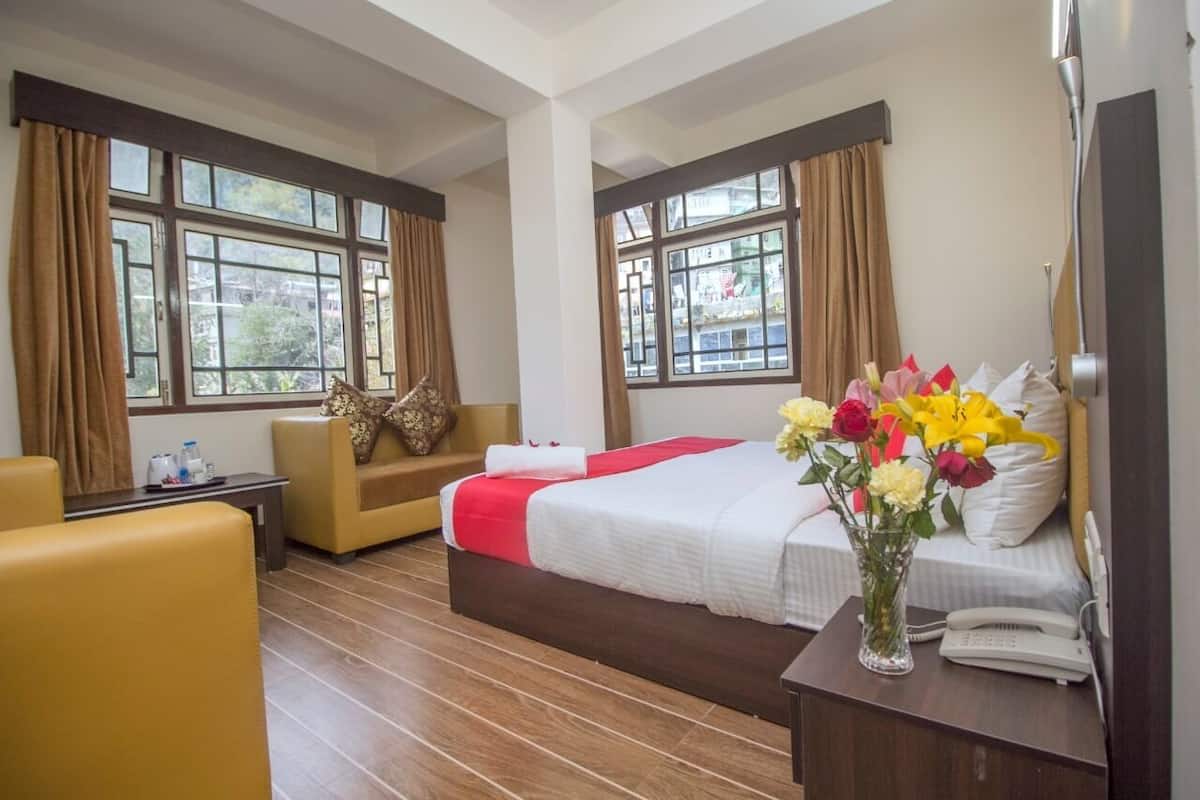 Ein Hotelzimmer mit Bett, einer Couch, einem Tisch mit Blumenvase und einem Telefon.