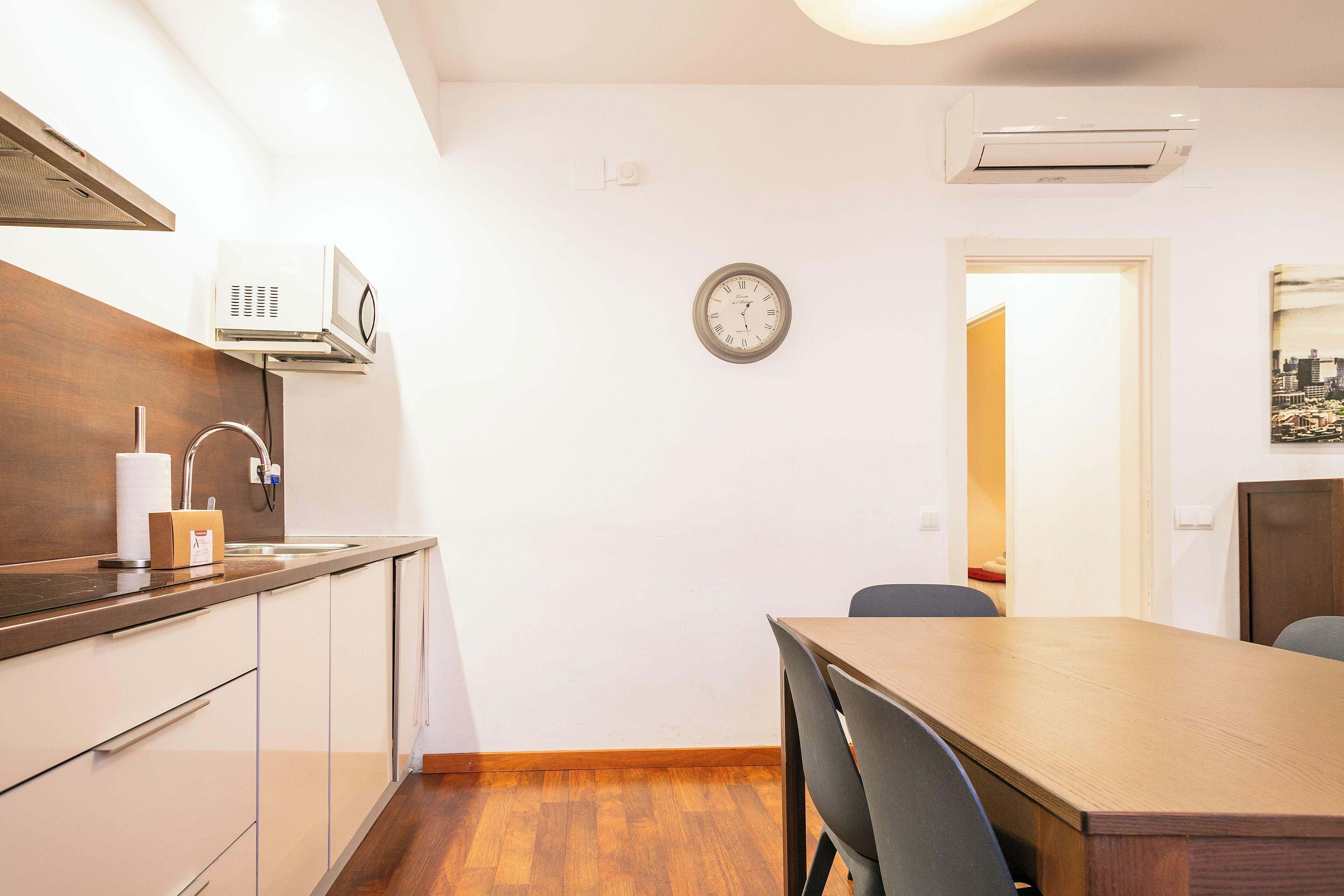 A modern kitchen with a wooden countertop, a built-in oven, and a wall-mounted clock.