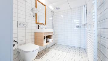 Een moderne badkamer met toilet, wastafel, spiegel en douche.