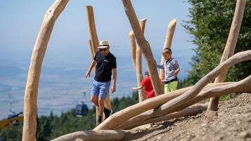 Un homme et un enfant marchent sur un pont en bois, avec un paysage pittoresque en arrière-plan.