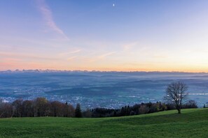 A panoramic view of a town with a prominent hill in the foreground and a mountain range in the distance. - Hotel Weissenstein (Oberdorf)
