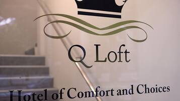 A logo with a crown and the text "Q Loft Hotel of Comfort and Choices" on a wall.