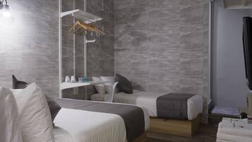 A modern hotel room with two beds, a mirror, a wooden dresser, and a hanging coat rack.