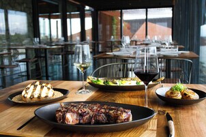 A restaurant setting with tables set for dining, plates of food, and wine glasses.