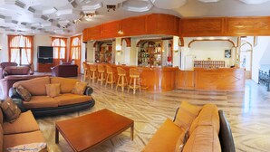 Ein großzügiger Wohnbereich mit Bar, Ledersofas und Fernseher.