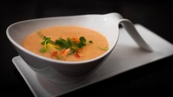 A bowl of soup with garnishes on a white plate.