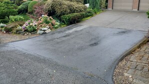 Un carrer residencial amb un camí corbat que condueix a un garatge.