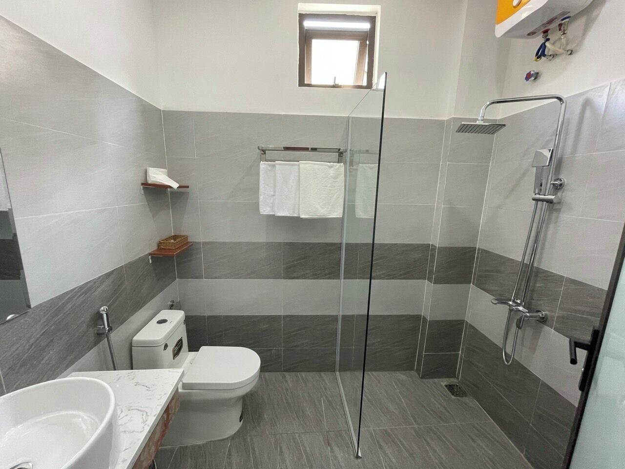 A modern bathroom with a glass-enclosed shower, a toilet, and a sink.