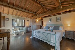 A bedroom with a bed, bedside tables, a wooden floor, and a ceiling with exposed beams.