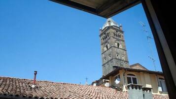 Una veduta di un edificio con tetto in tegole e un'alta torre con finestre ad arco.