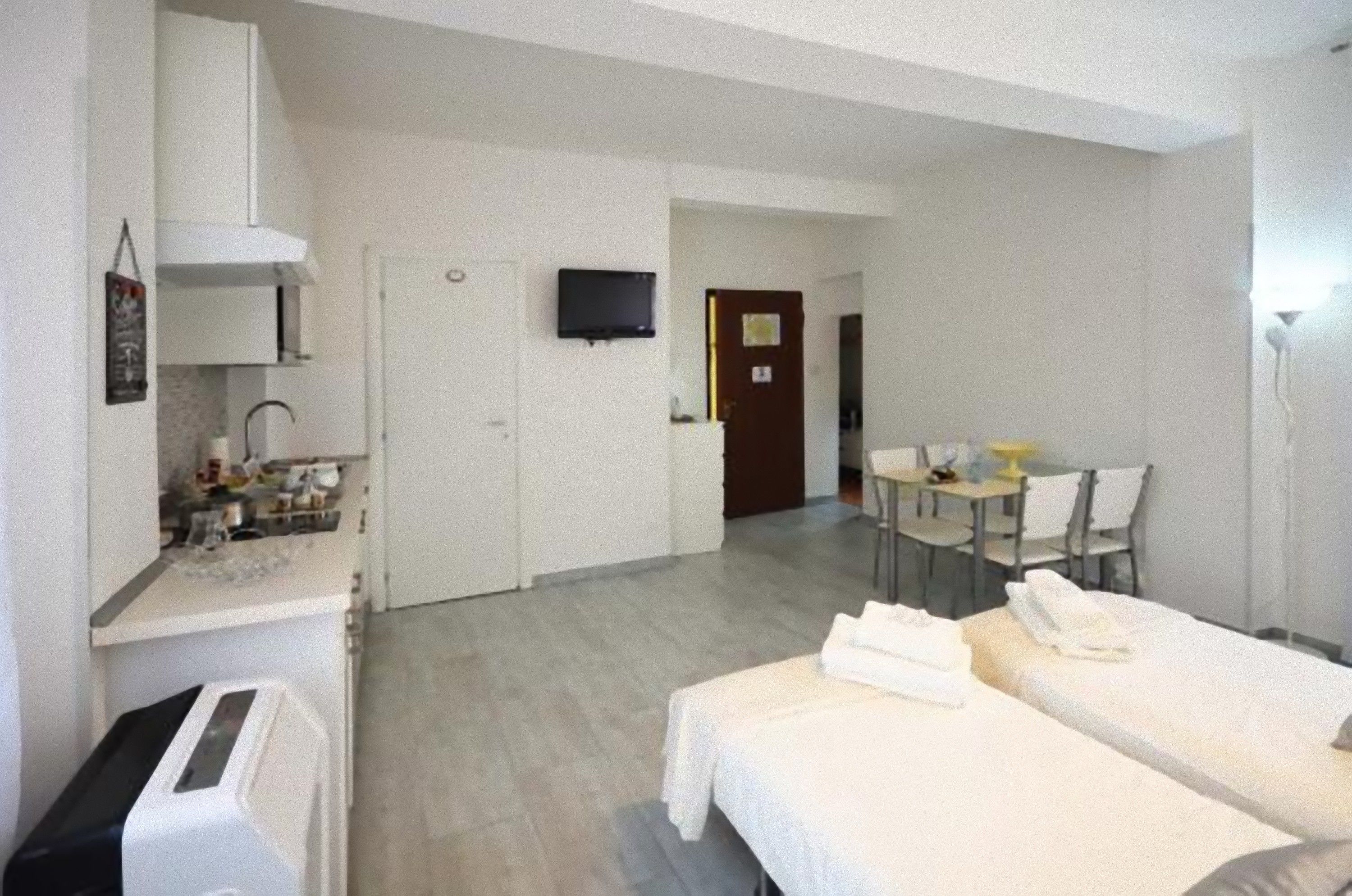 Een hotelkamer met twee bedden, een kitchenette, een eethoek en een televisie.