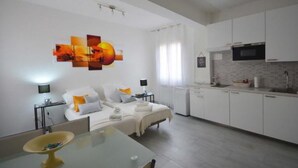 Een moderne, goed verlichte kamer met een bed, nachtkastjes en een zithoek.