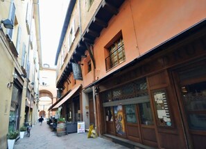 A narrow street with buildings on either side, featuring balconies and wooden shutters. - 4 Tourist House Apartment Centre Bologna (Bologna)
