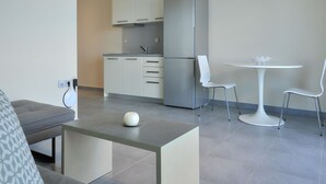Eine moderne Küche mit weißen Schränken, einem Edelstahlkühlschrank und einem Essbereich mit weißem Tisch und Stühlen.
