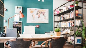 A workspace with a desk, two chairs, a world map, a bookshelf, and a coffee machine. - The Hostello (Verona)