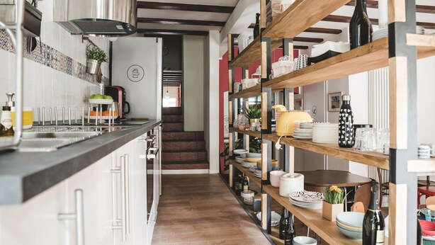 A kitchen with a wooden staircase, shelves with dishes, and a modern design. - The Hostello (Verona)