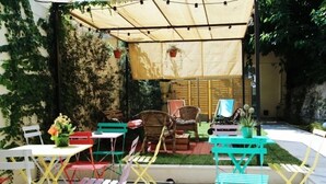 An outdoor patio with colorful chairs and tables, a covered seating area, and potted plants. - The Hostello (Verona)