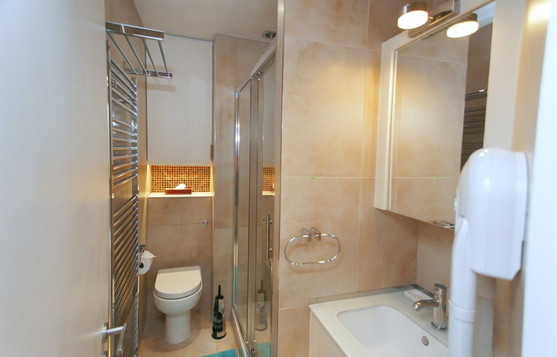 A modern bathroom with a glass shower enclosure, a toilet, a sink with a mirror, and a towel rack.