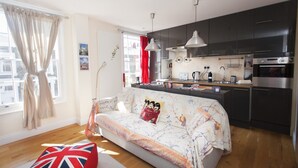 A modern kitchen with dark cabinets, a central island, and a built-in oven. - Camden Town Colorful Market Atmosphere (London)