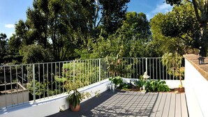 A rooftop garden with a wooden deck, white railing, and various potted plants. - Camden Town Colorful Market Atmosphere (London)