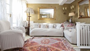 A cozy living room with a sofa, armchairs, a patterned rug, a lamp, and a mirror on the wall. - Chelsea for History and Art Lovers (London)