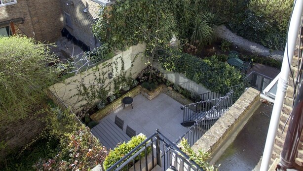 A residential area with brick houses, a small courtyard with a bench, and a staircase leading to a higher level. - Chelsea for History and Art Lovers (London)