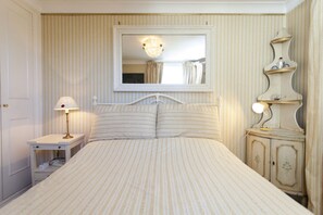 A bedroom with a bed, a nightstand, a dresser, a mirror, and a lamp.