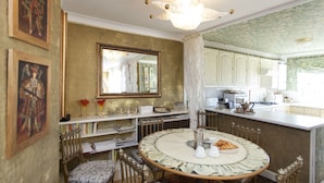 A dining area with a round table, chairs, a chandelier, and a mirror on the wall. - Chelsea for History and Art Lovers (London)