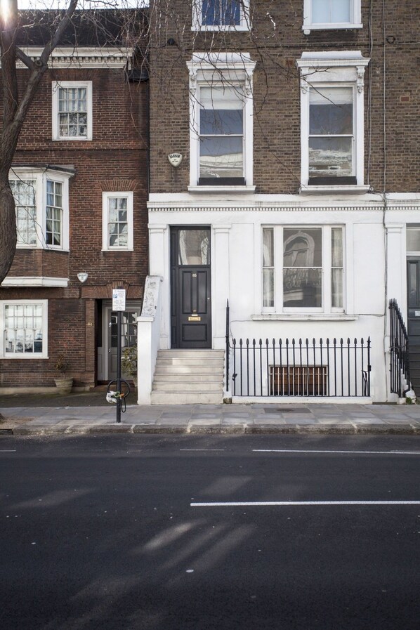 A two-story townhouse with a black front door, white trim, and a small front yard with a metal fence.