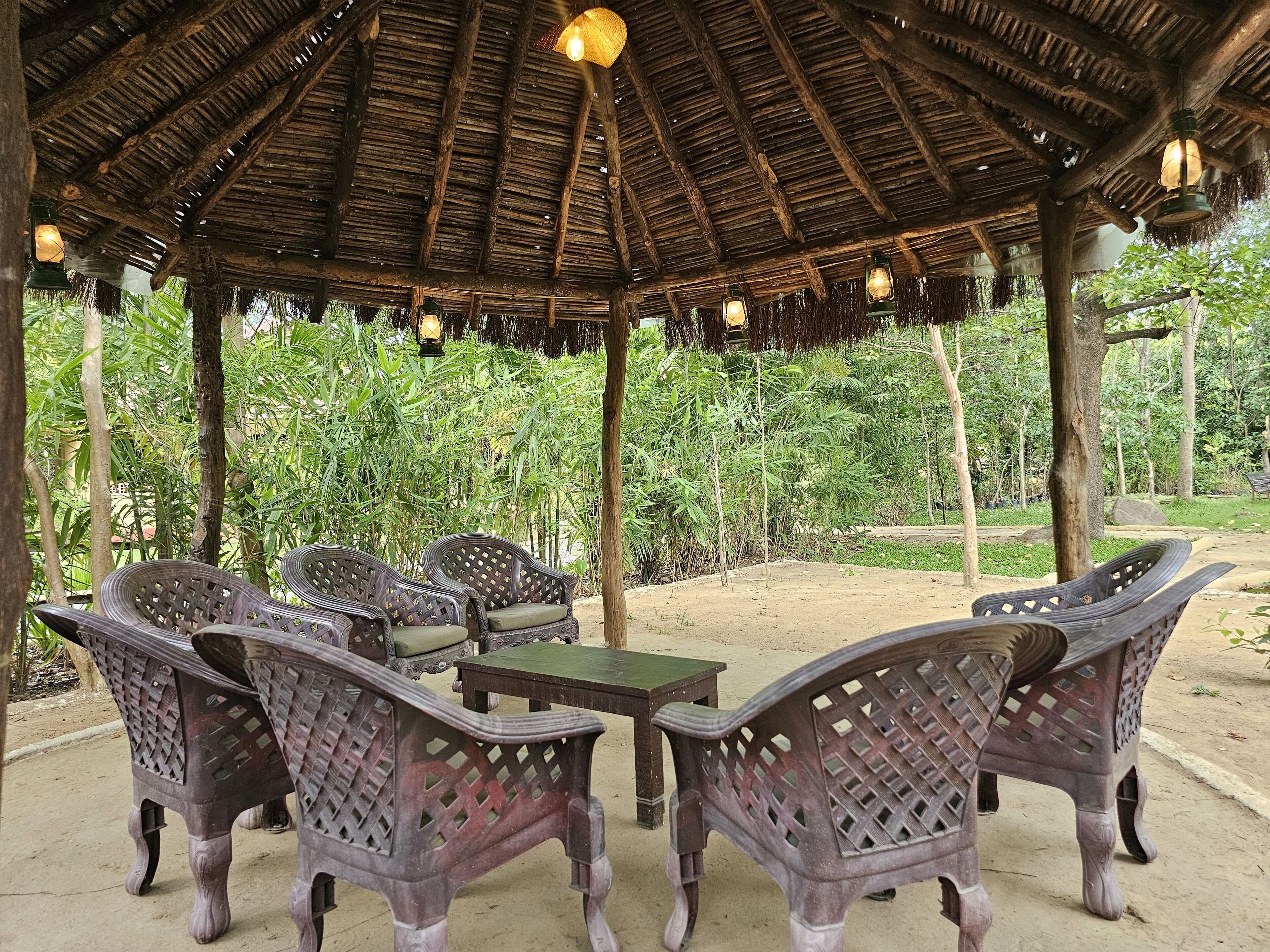 A covered outdoor seating area with wicker furniture and hanging lanterns.