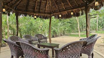 A covered outdoor seating area with wicker furniture and hanging lanterns.