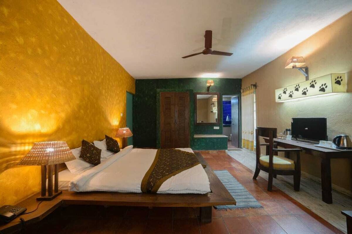 Une chambre d’hôtel équipée d’un lit, d’une lampe de chevet, d’un bureau, d’une chaise, d’une télévision et d’un miroir.